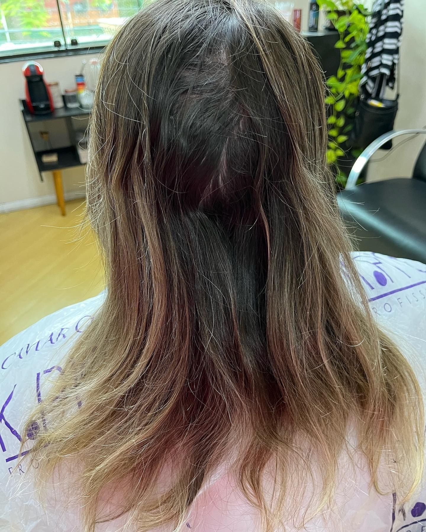 Antes: mechas antigas manchadas e raiz escura, cabelo visto de costas