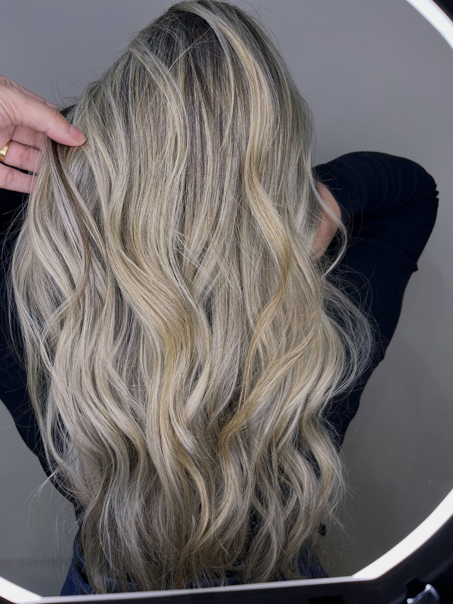 Loiro perolado acinzentado com raiz esfumada em cabelo longo ondulado, visto de costas