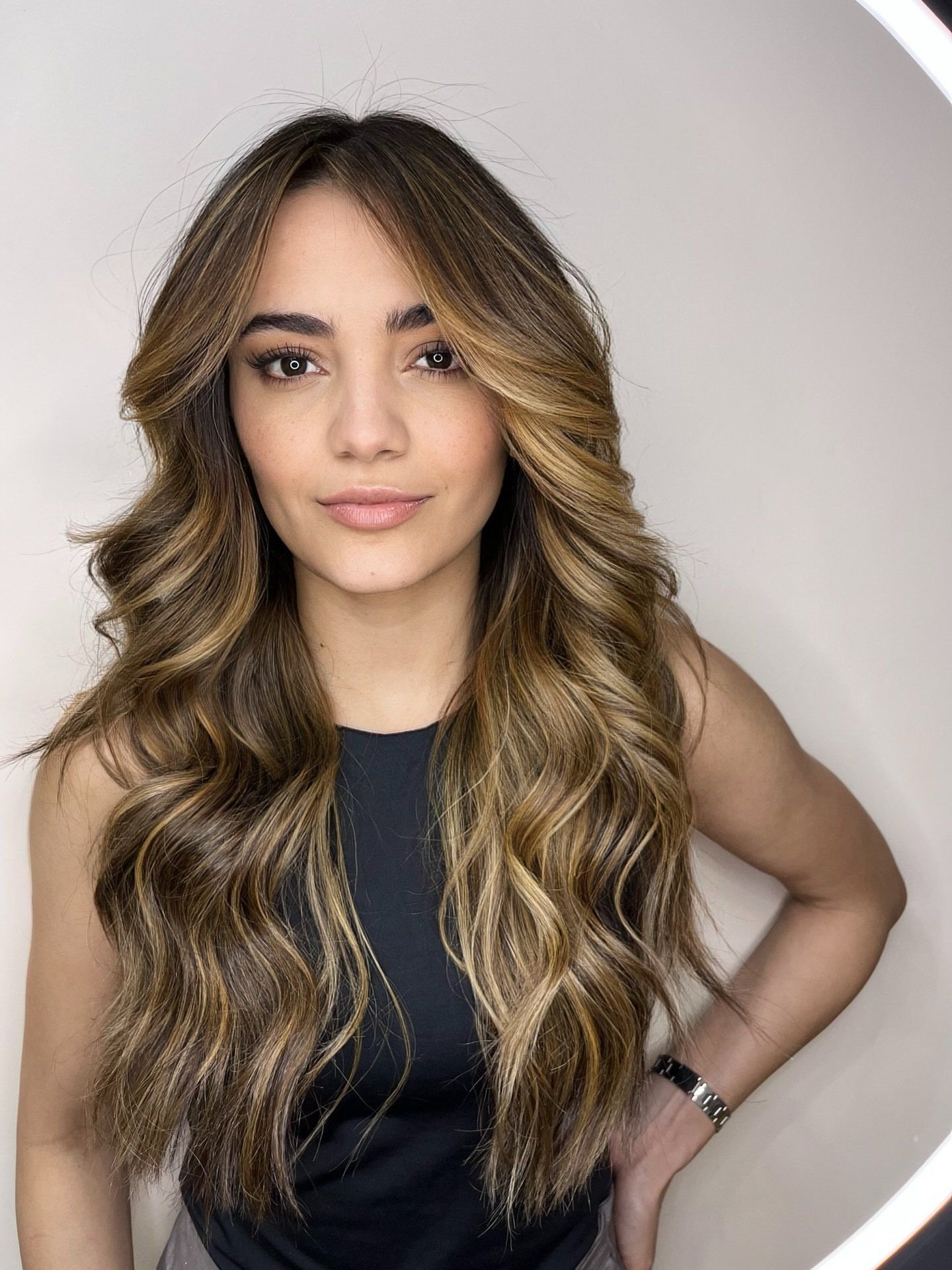 Cliente com morena iluminada caramelo e franja cortina, cabelo longo com ondas